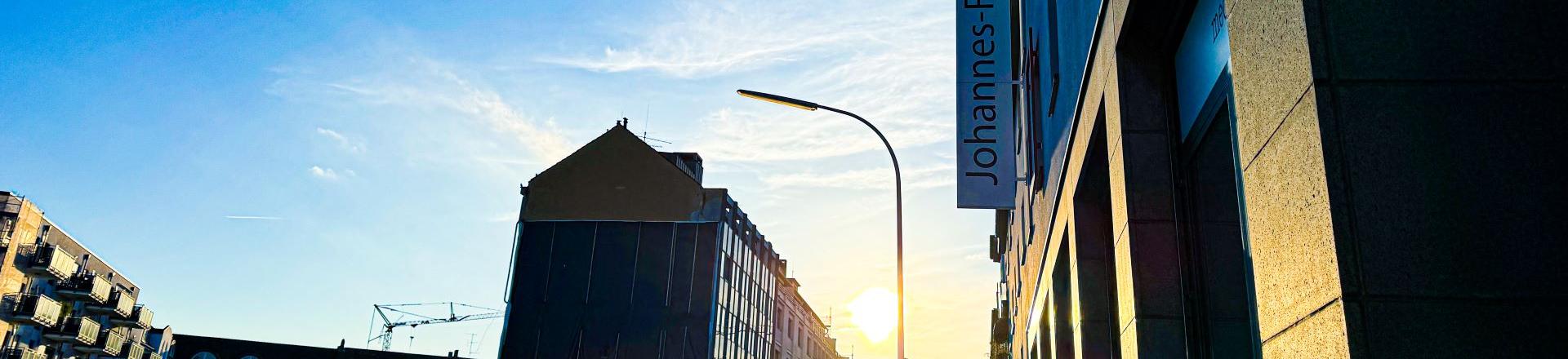 Man blickt in eine Straße vom Johannes-Foyer aus. Am Ende der Straße strahlt die Sonne