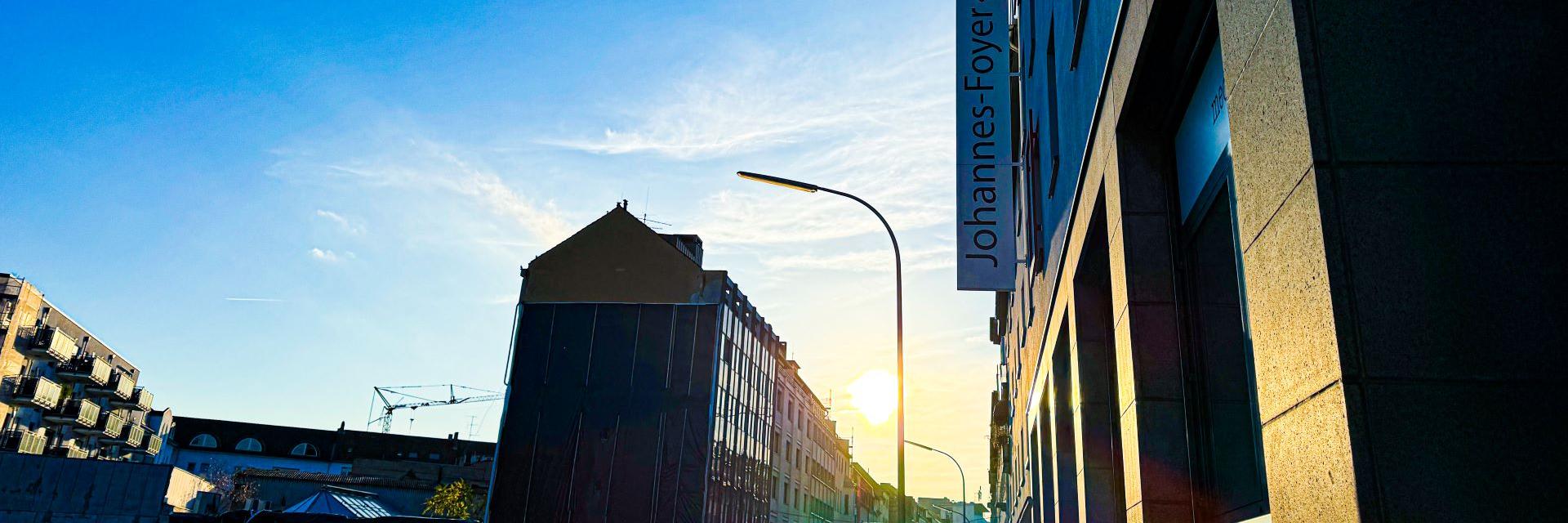 Man blickt in eine Straße vom Johannes-Foyer aus. Am Ende der Straße strahlt die Sonne