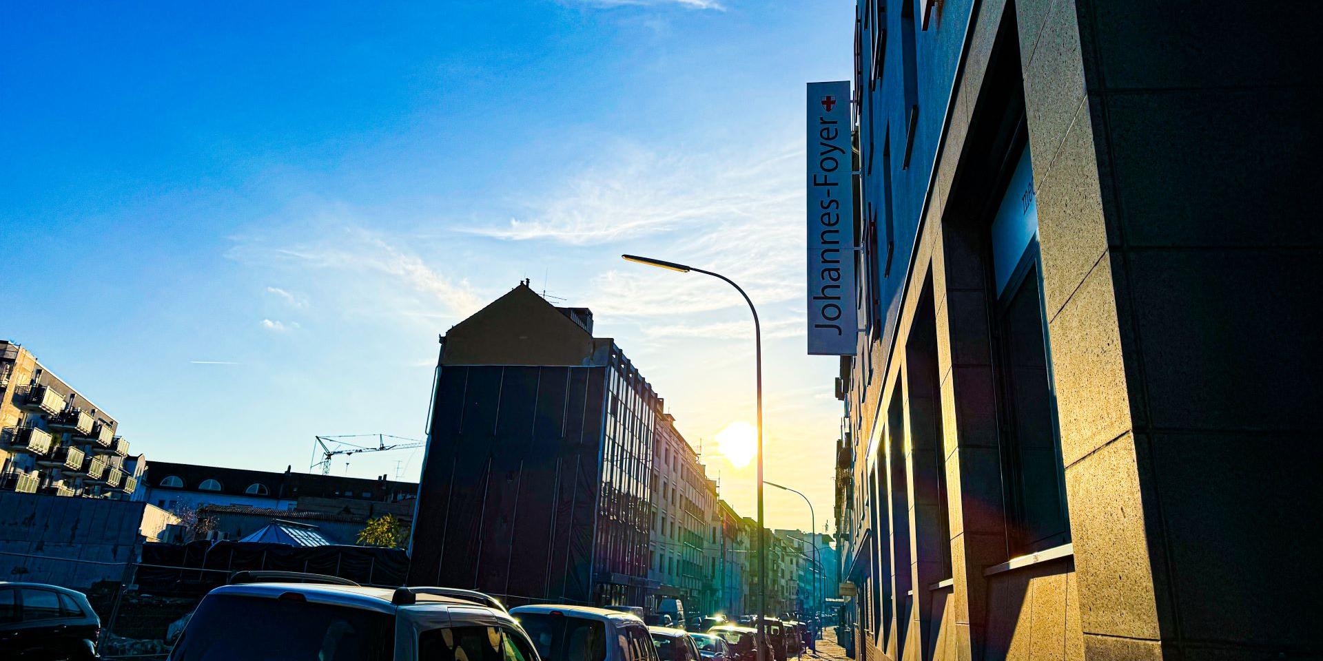 Man blickt in eine Straße vom Johannes-Foyer aus. Am Ende der Straße strahlt die Sonne