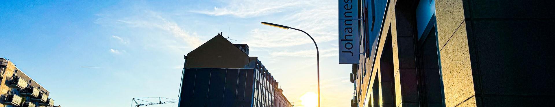 Man blickt in eine Straße vom Johannes-Foyer aus. Am Ende der Straße strahlt die Sonne