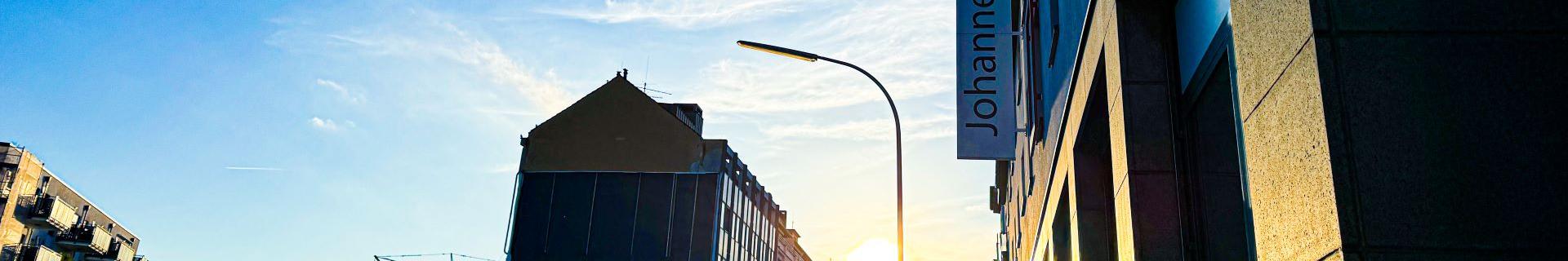 Man blickt in eine Straße vom Johannes-Foyer aus. Am Ende der Straße strahlt die Sonne