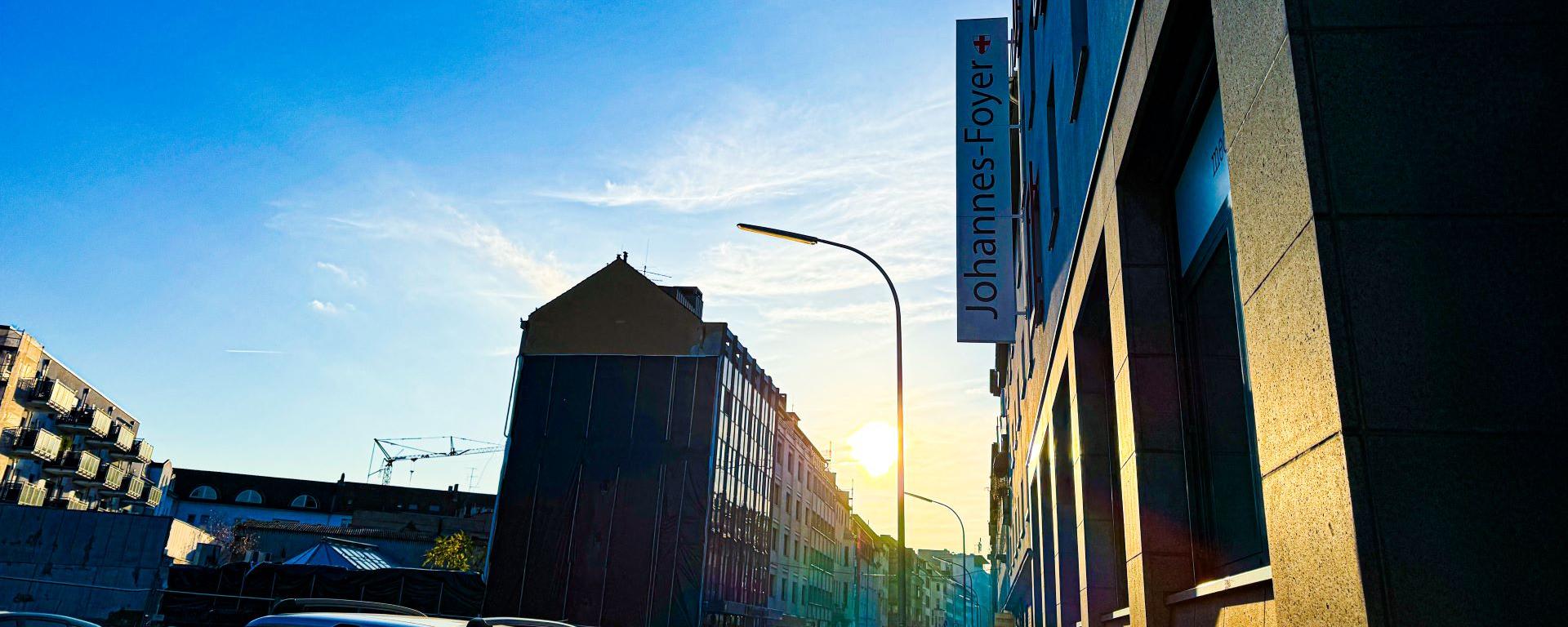 Man blickt in eine Straße vom Johannes-Foyer aus. Am Ende der Straße strahlt die Sonne