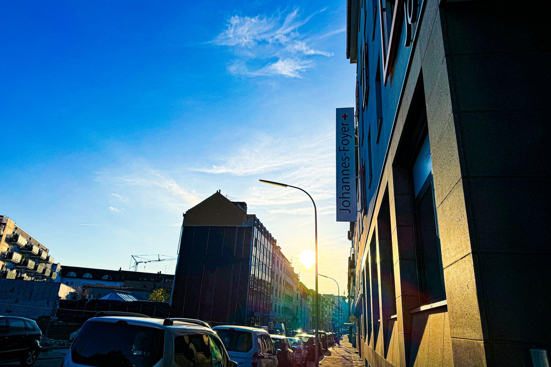 Man blickt in eine Straße vom Johannes-Foyer aus. Am Ende der Straße strahlt die Sonne