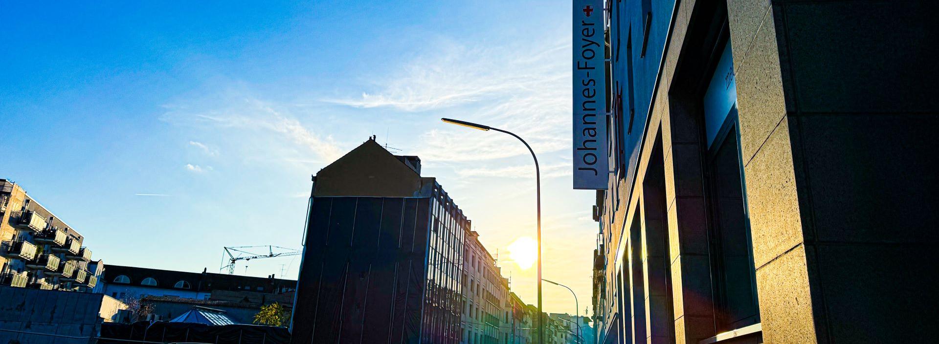 Man blickt in eine Straße vom Johannes-Foyer aus. Am Ende der Straße strahlt die Sonne