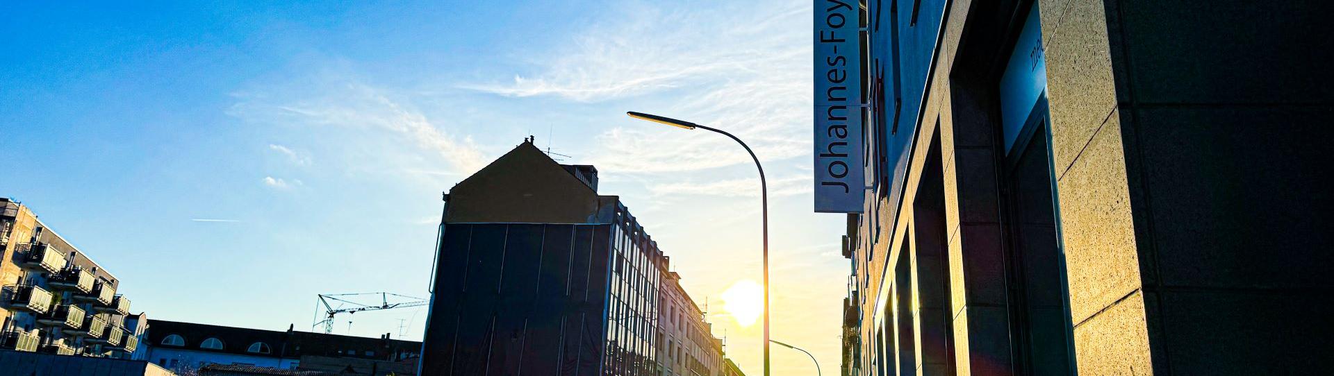 Man blickt in eine Straße vom Johannes-Foyer aus. Am Ende der Straße strahlt die Sonne